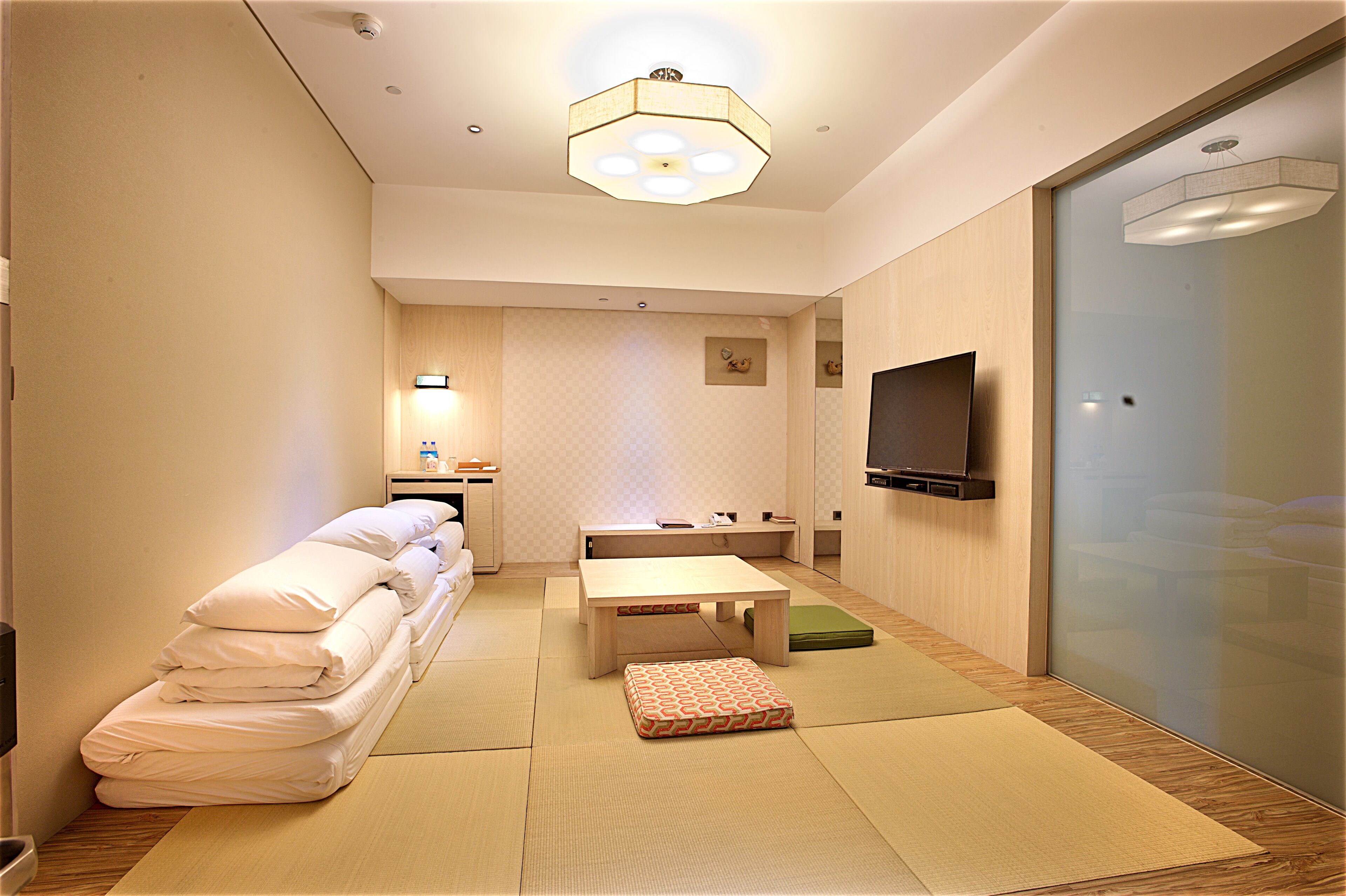 Una habitación de hotel con cama, una mesita, un sofá, un televisor y una puerta corredera.