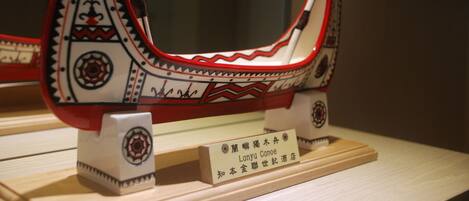 Une maquette d’un bateau traditionnel, ornée de motifs complexes et portant une plaque avec son nom.