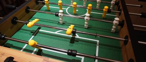 Une table de baby-foot avec un tapis de jeu vert et plusieurs tiges sur lesquelles sont fixées des figurines jaunes et blanches.