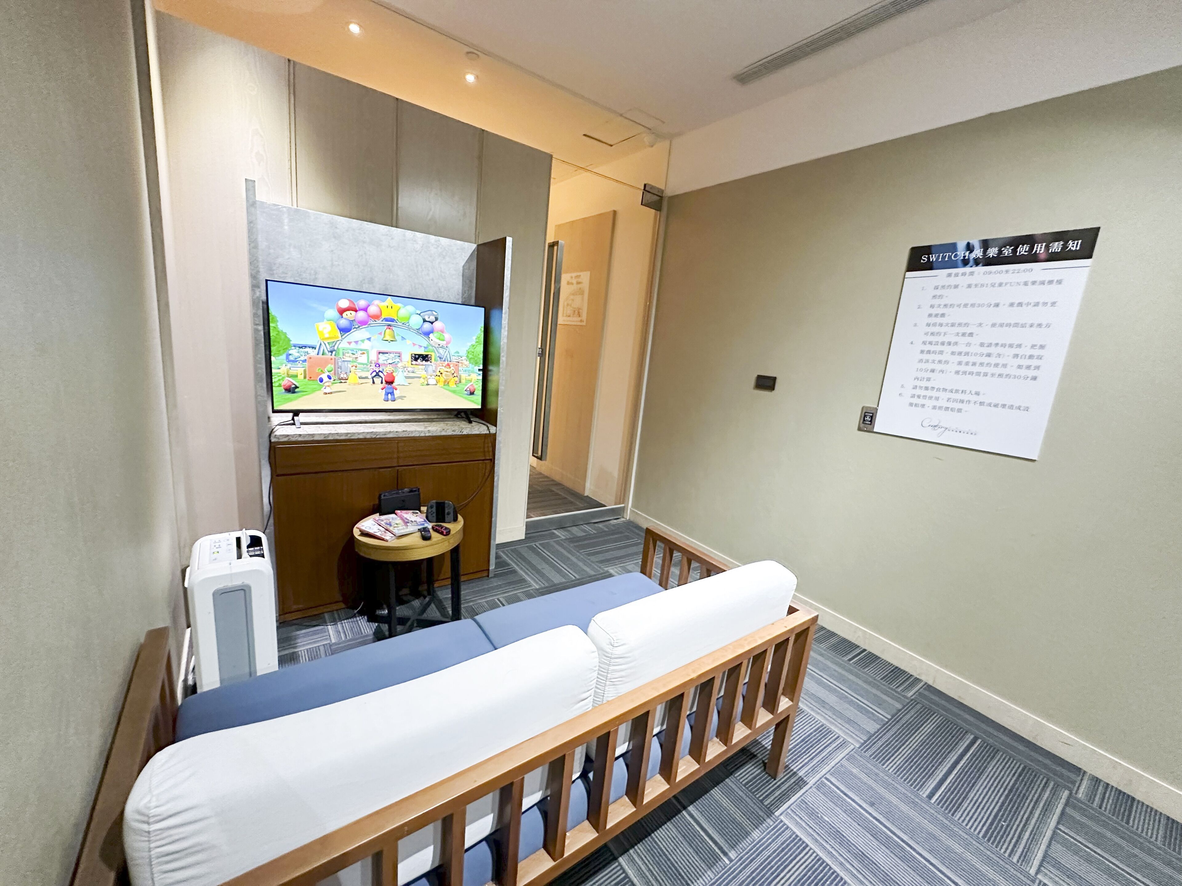 Una habitación de hotel con una cama, una pequeña mesa con televisión y un cartel en la pared.