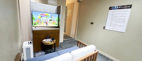 Una habitación de hotel con una cama, una pequeña mesa con televisión y un cartel en la pared.