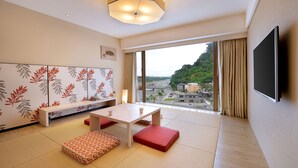 A modern hotel room with a large window, a flat-screen TV, a white table, and a bench. - Chihpen Century Hotel (Taimali)