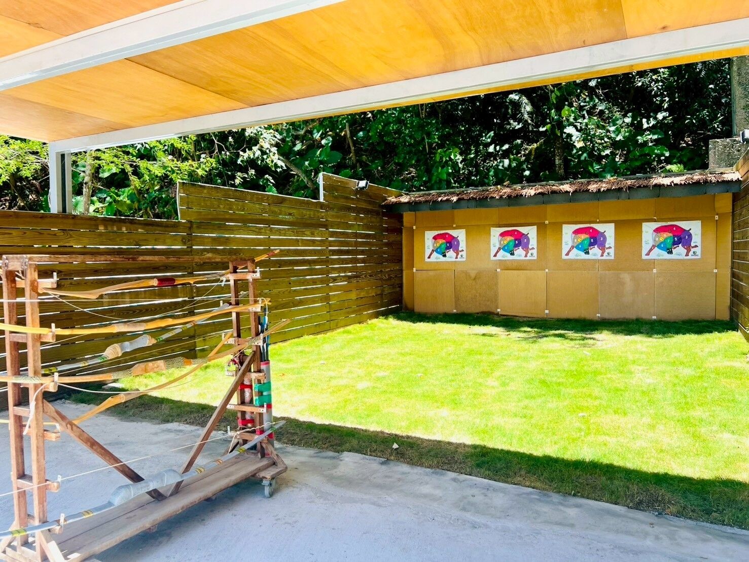 Un espace extérieur abrité doté d’une structure en bois, qui pourrait être un ensemble de jeux, et d’un mur orné d’œuvres d’art colorées.