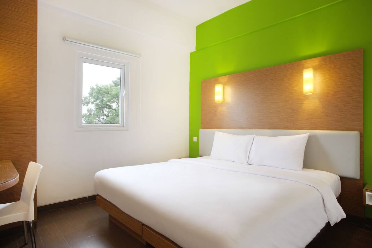 Ein modernes Hotelzimmer mit einem großen Bett, einem kleinen Tisch und einem Sessel.