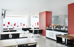 A modern restaurant with a clean, minimalist design, featuring white and red accents, and a central buffet area. - Amaris Hotel Malang (Malang)