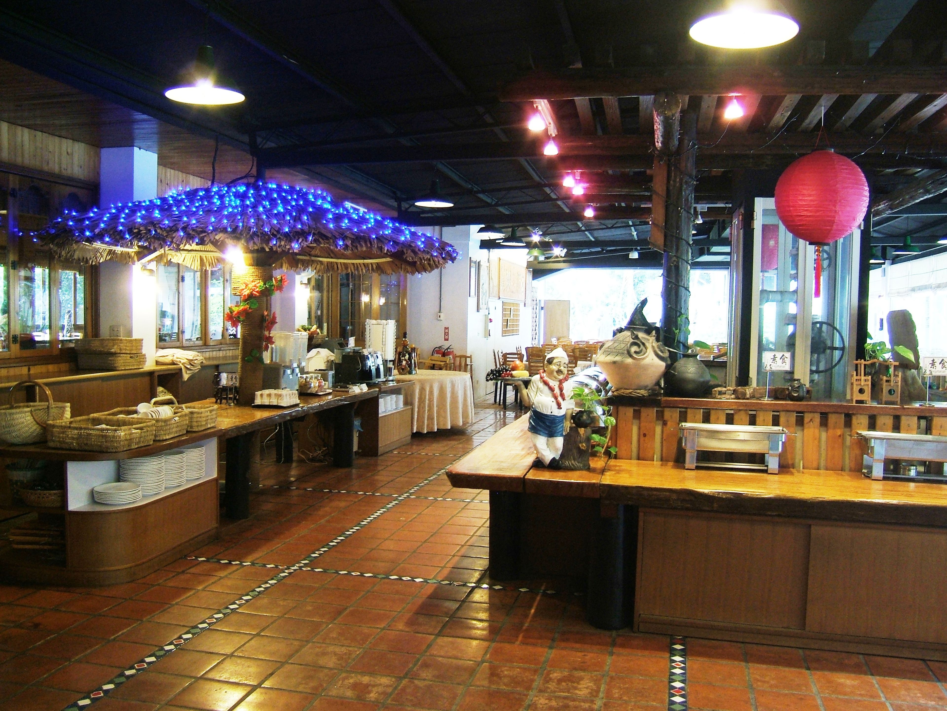 A restaurant interior with a wooden counter, tiled floor, and decorative lights.
