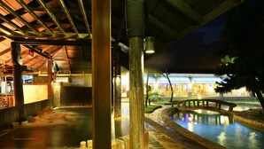 A traditional Japanese onsen with a stone bath, wooden pillars, and a stone pathway leading to a bridge over a water feature. - Rainbow Resort (Taimali)