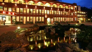A hotel with a red brick facade, arched windows, and a well-lit entrance. - Rainbow Resort (Taimali)