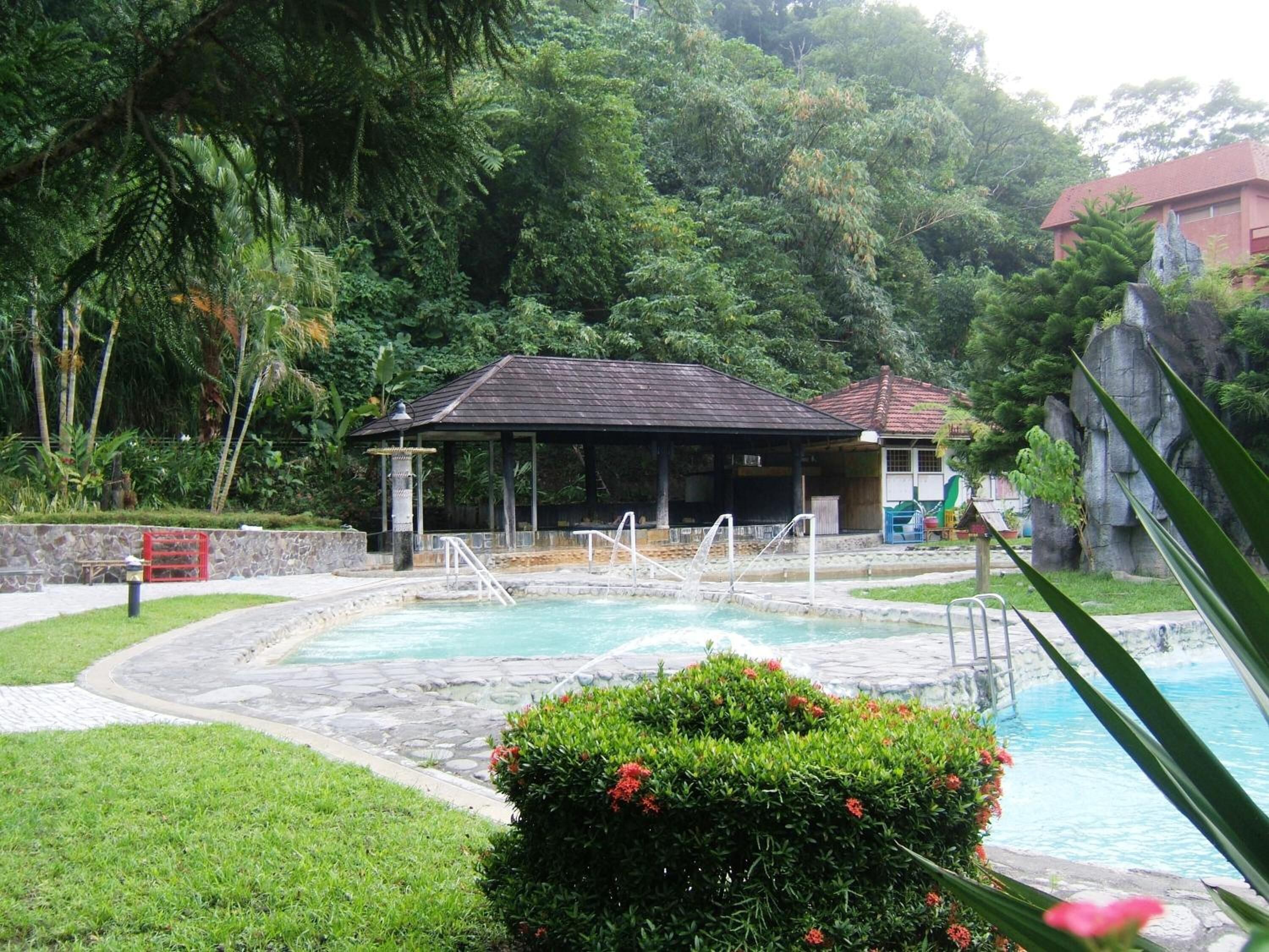 A pool area with a covered pavilion, a stone pathway, and lush greenery.