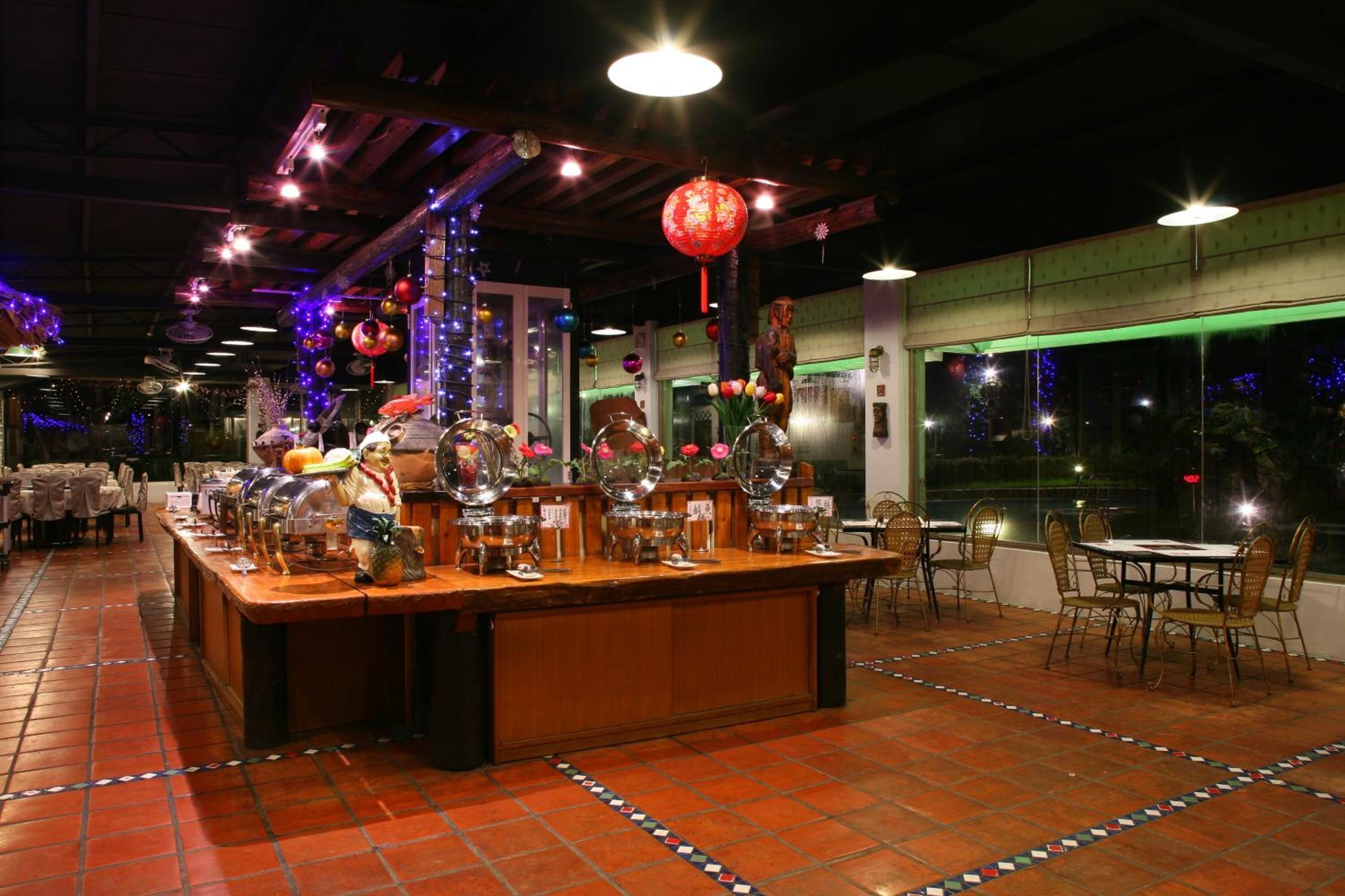 A restaurant with a long counter, multiple round tables, and chairs.