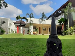 A modern building with a covered patio area, surrounded by well-maintained grass and palm trees.