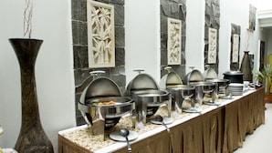 A buffet setup with multiple serving stations, a large decorative vase, and stone wall decorations. - Gowongan Inn Yogyakarta (Yogyakarta)