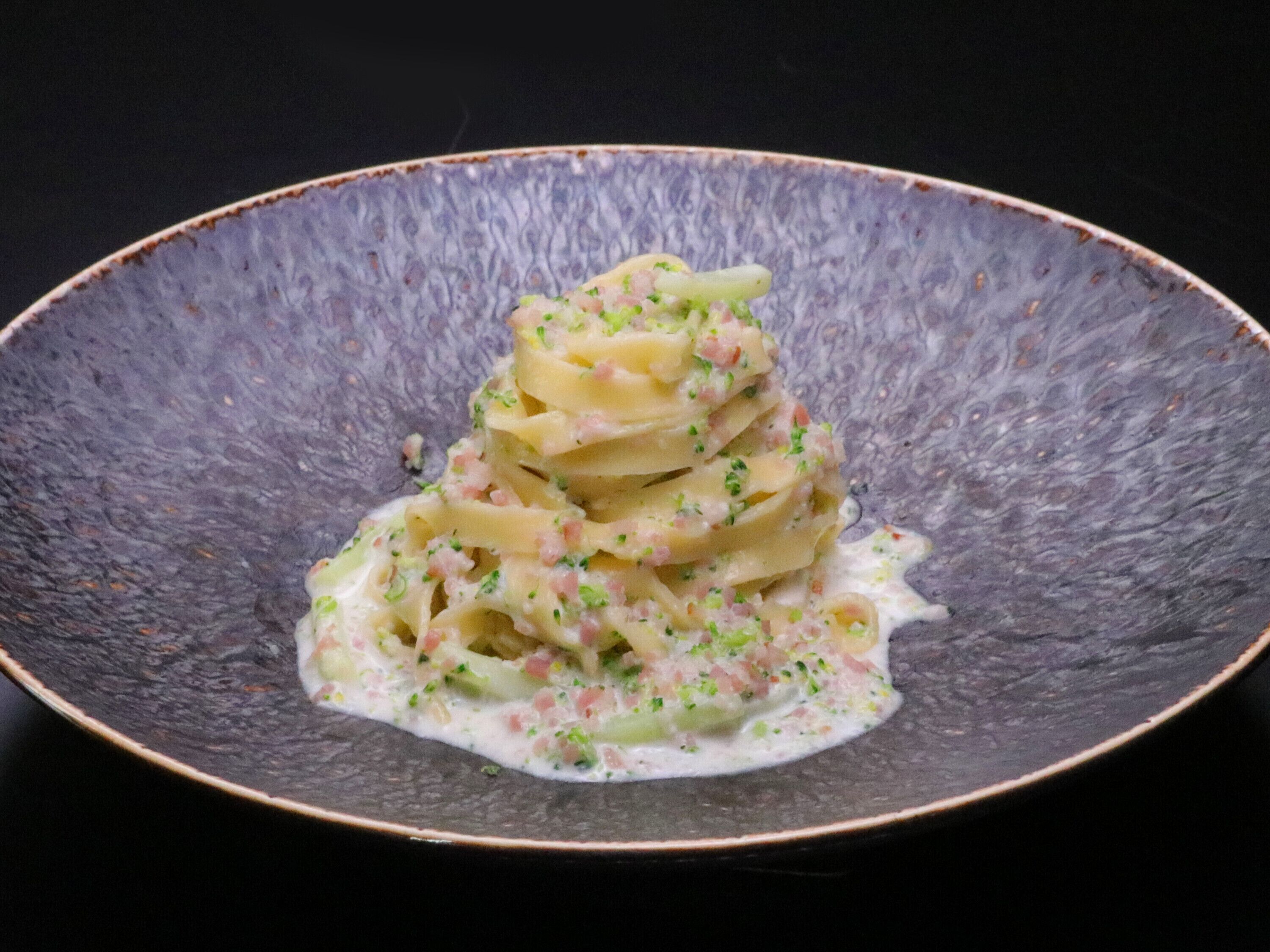 Une assiette de pâtes nappées d’une sauce crémeuse et parsemée d’herbes fraîches hachées.