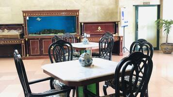A dining area with a table and chairs, a fish tank, a clock, and a sign indicating a rest room.
