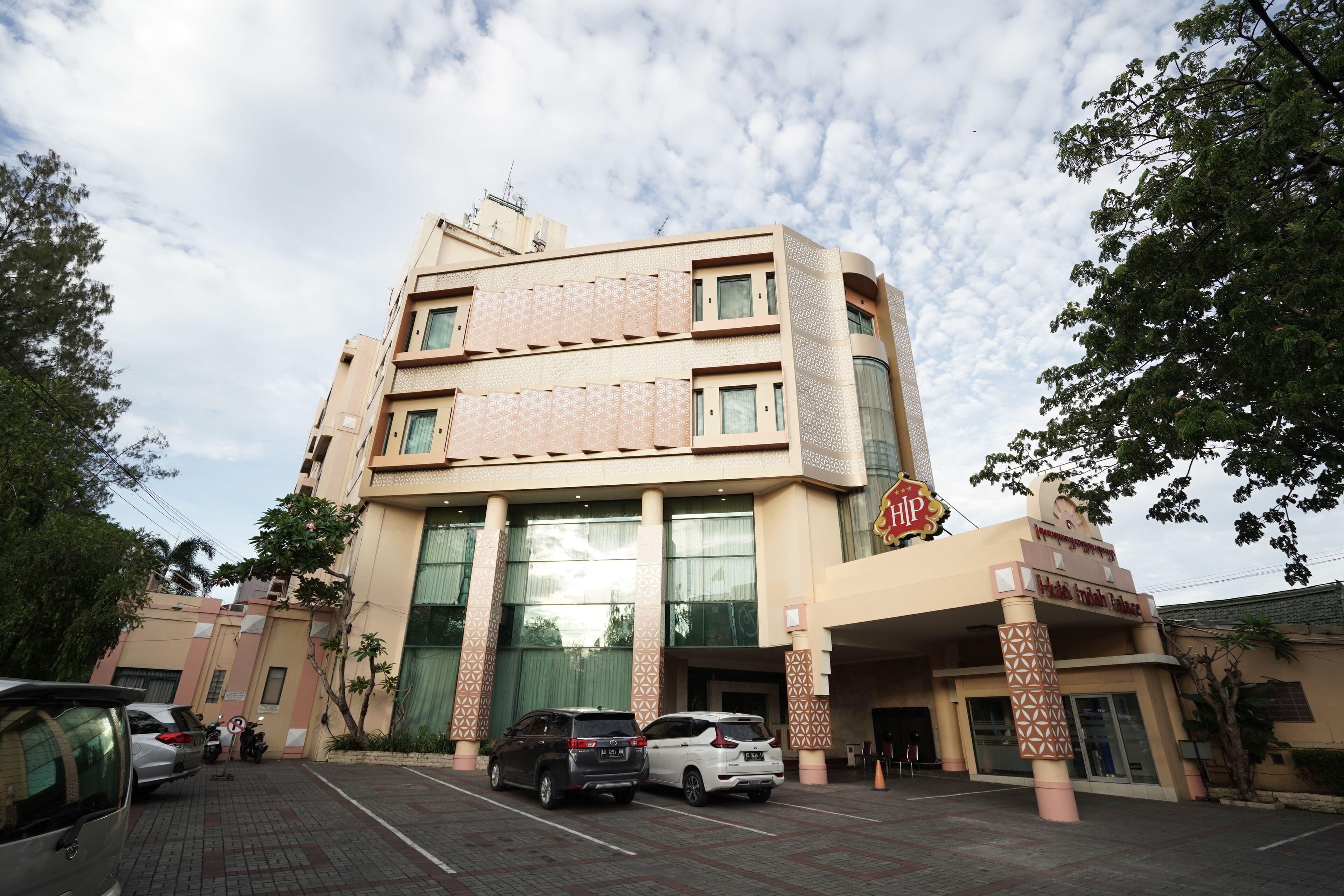 A multi-story hotel with a large entrance, parking area, and a sign indicating a restaurant.