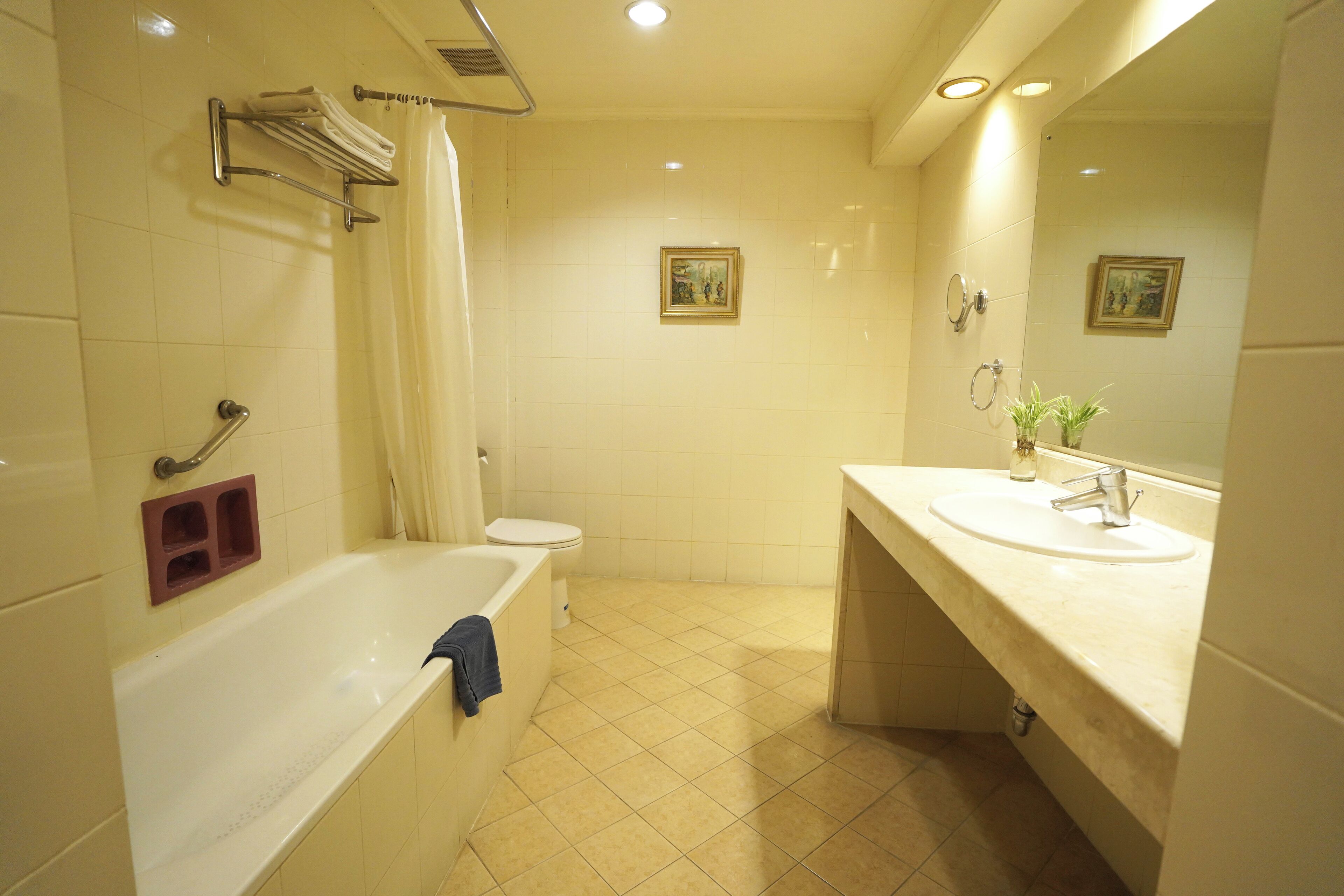 Un baño con bañera, inodoro, lavabo y dos cuadros enmarcados en la pared.
