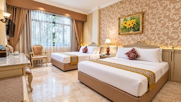 A hotel room with two beds, a desk, a chair, a lamp, and a painting on the wall.