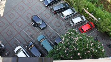A parking lot with multiple cars and a large bush with pink flowers.