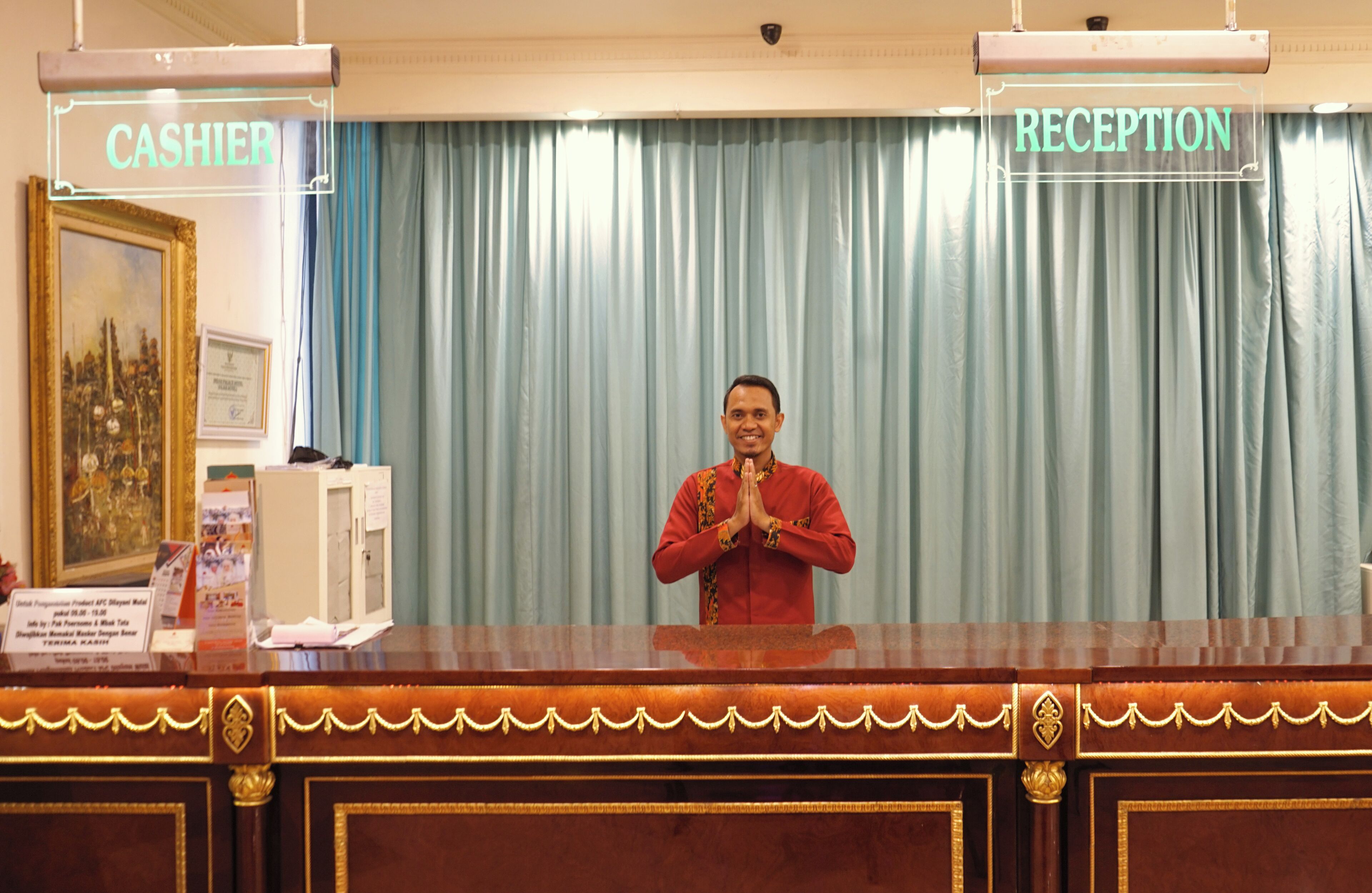 A reception area with a wooden reception desk, a framed cityscape picture, and a sign indicating 'CASHIER' and 'RECEPTION' areas.