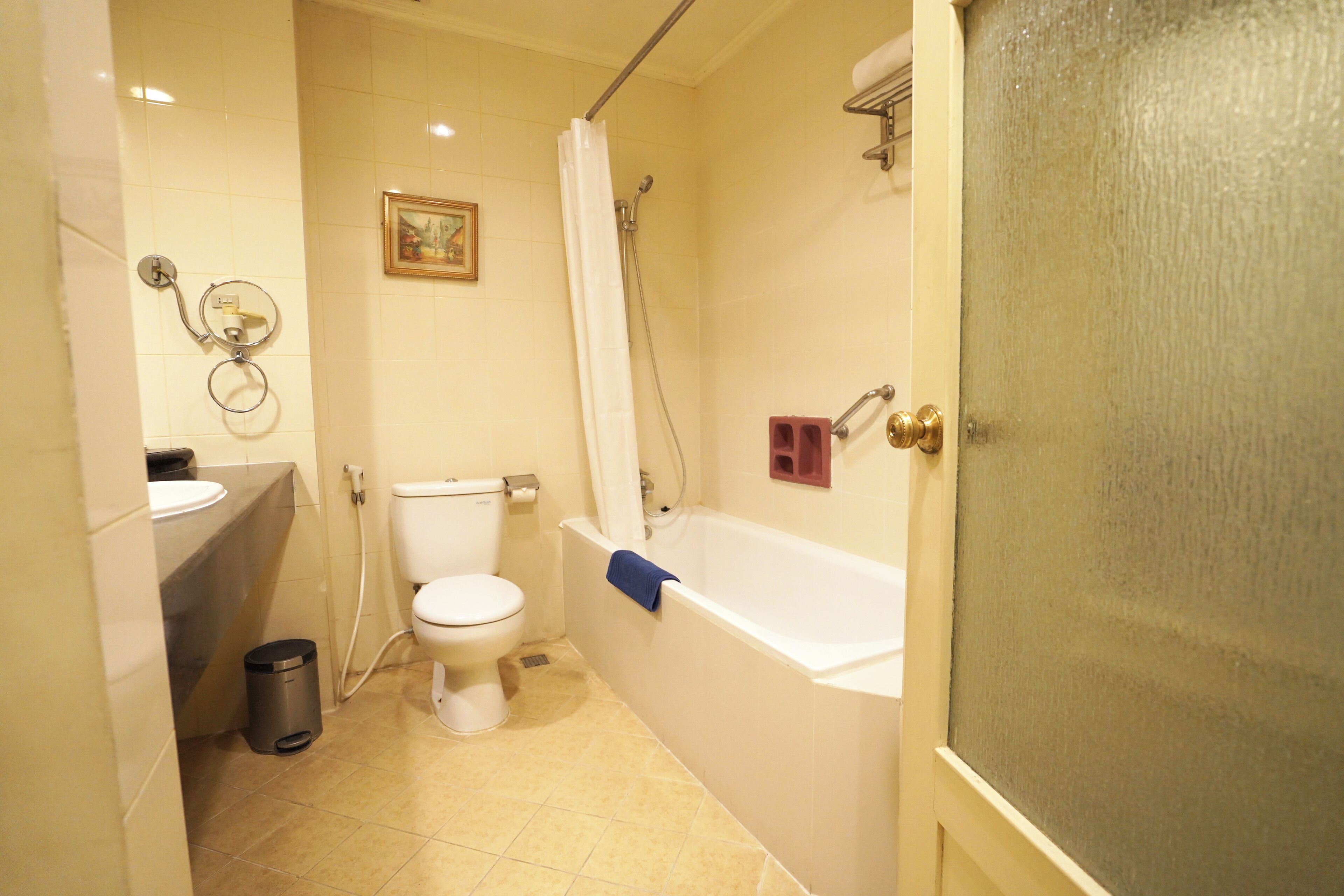 Et badeværelse med toilet, håndvask, badekar og bruser.
