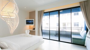A modern hotel room with a large bed, a television, and a balcony with a view of the city. - The House Patong (Patong)