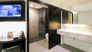 A modern bathroom with a large mirror, a sink, and a shower area. - The House Patong (Patong)