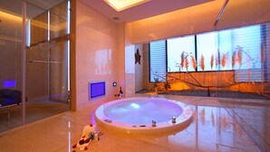 Un spa moderno con una amplia bañera de hidromasaje circular, un box de ducha de vidrio y vistas a pastizales.