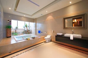 A modern bathroom with a bathtub, toilet, and sink, featuring a large mirror and potted plants. - Amain Boutique Motel Tucheng (New Taipei City)