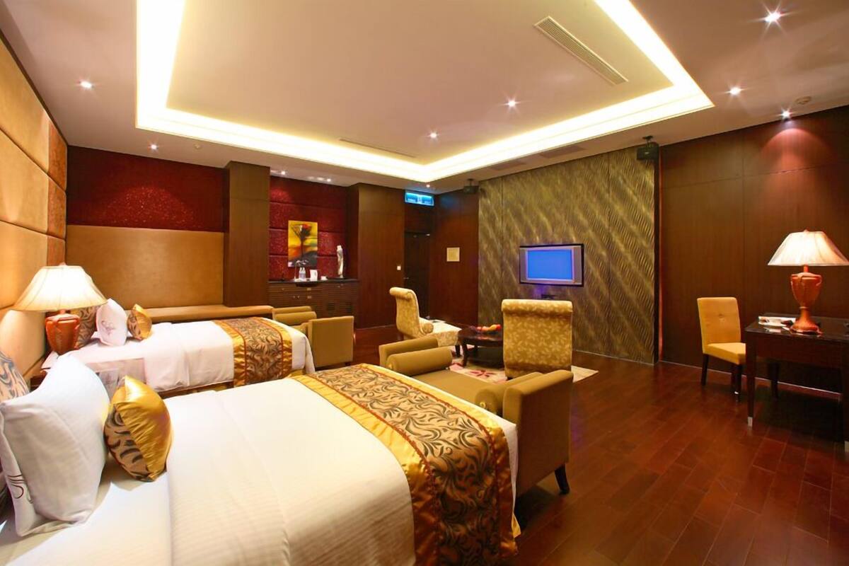 Quarto de hotel com duas camas, televisão, escrivaninha e cadeira.