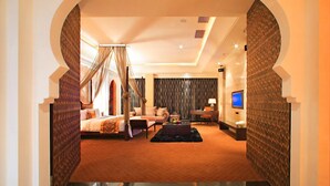 Una habitación de hotel con cama, zona de estar, televisor y escritorio.