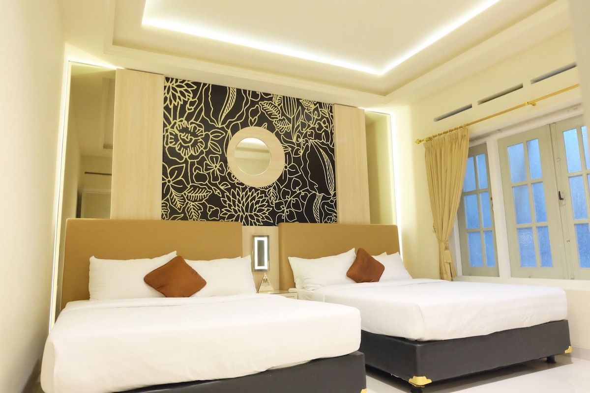Habitación de hotel con dos camas, un espejo grande y vistas al exterior por una ventana.