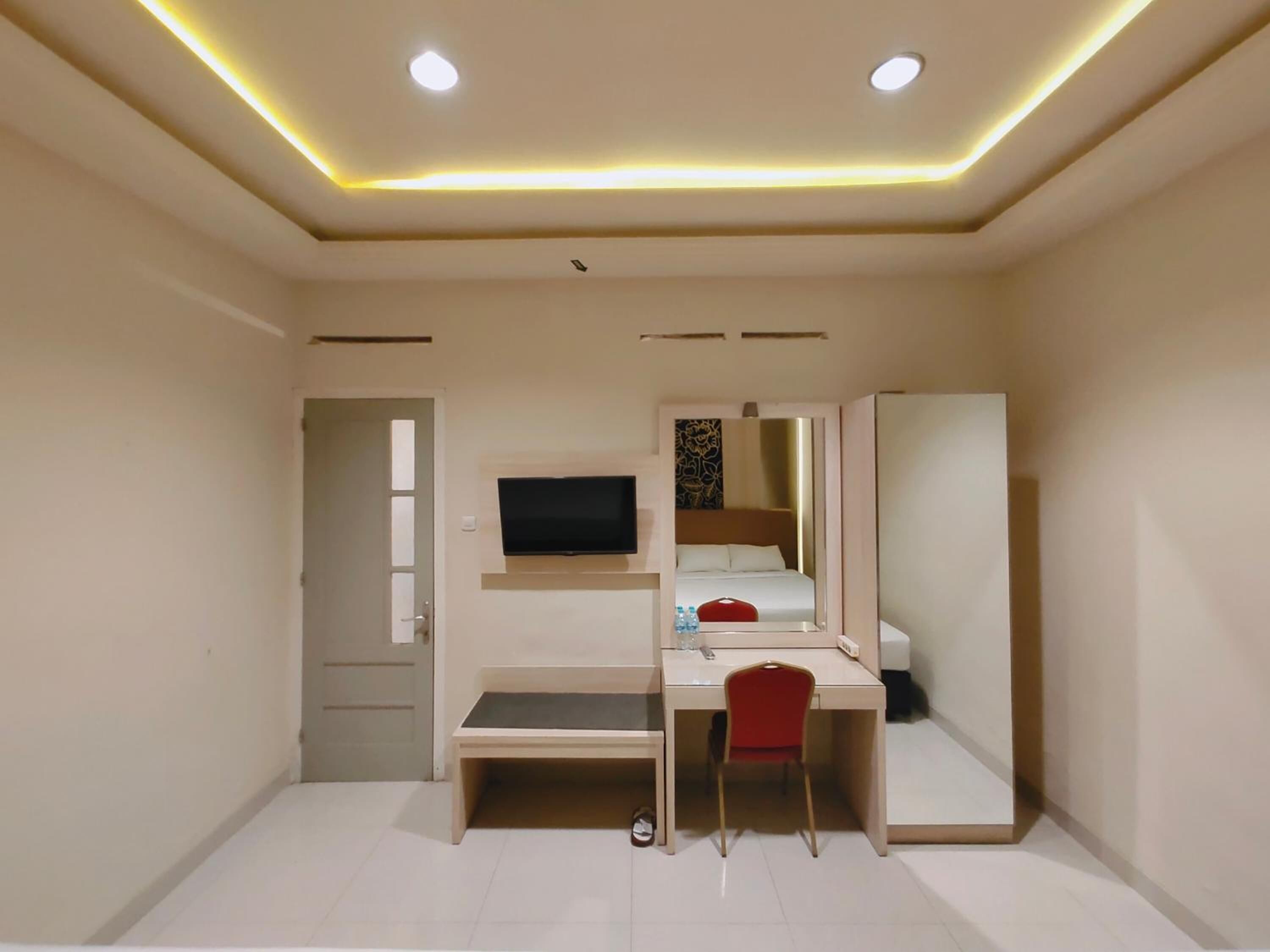 A compact hotel room with a desk, a bed, a television, and a wardrobe.