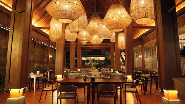 A restaurant with multiple tables and chairs, large hanging wicker lamps, and a wooden ceiling. - Hotel Indah Palace Tawangmangu (Tawangmangu)