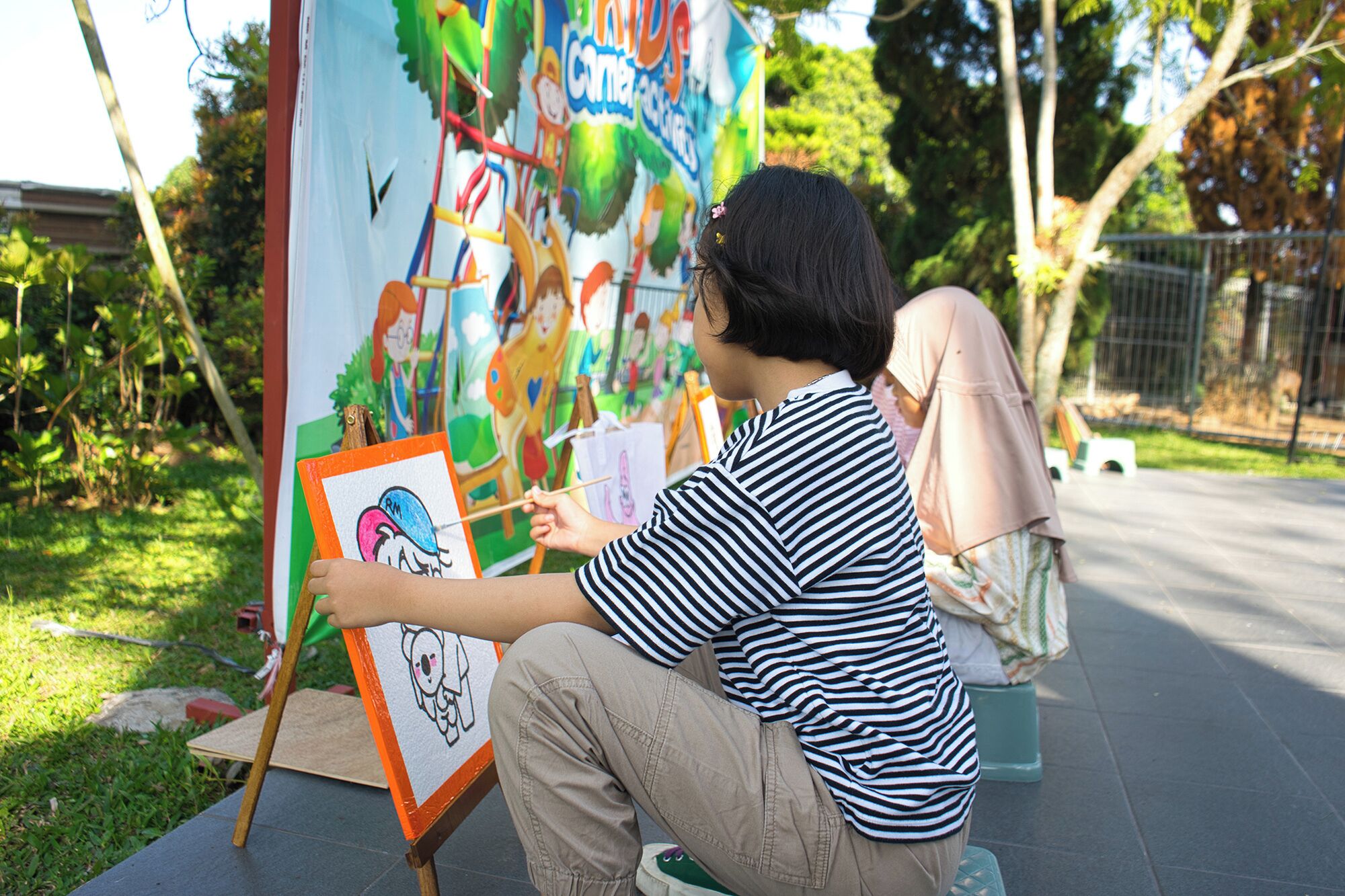 A person painting on an easel outdoors.