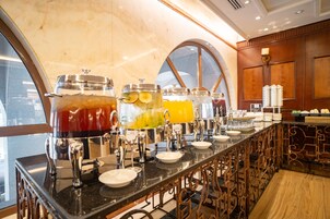 A buffet bar with multiple drink dispensers and a variety of food items.