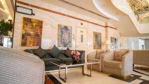 Un hall d’entrée moderne avec un sol en marbre, deux canapés, une table basse et de grandes œuvres d’art mural.