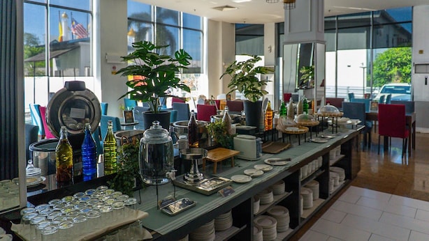 A buffet setup with various glassware, plates, and bottles. - Dormani Hotel Kuching (Kuching)