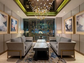 A modern lobby with two sofas, a central coffee table, and a decorative chandelier. - Hotel Santika Premiere Gubeng - Surabaya (Surabaya)