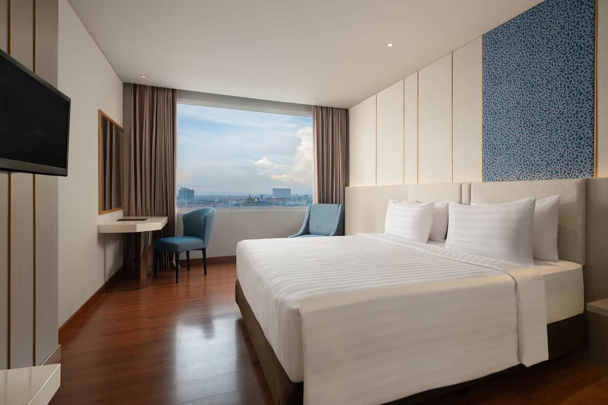 Una habitación de hotel con una cama grande, un escritorio, una silla y un televisor.