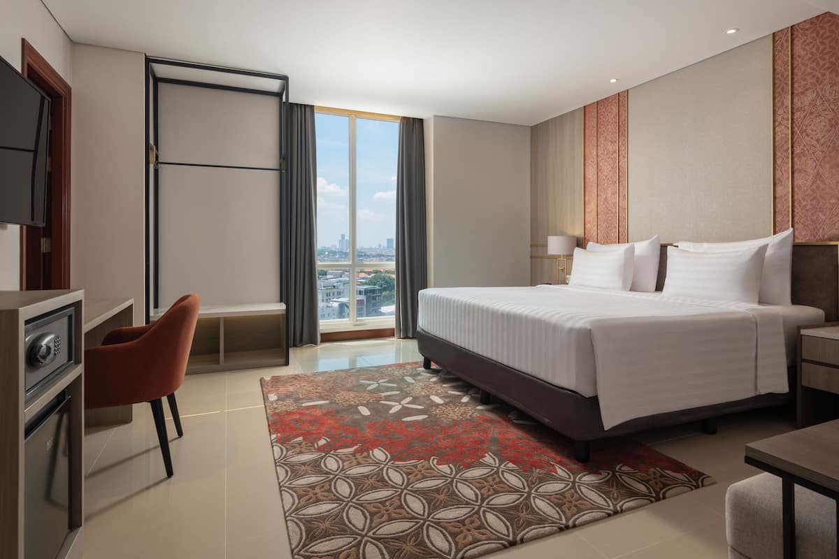 Una habitación de hotel moderna con una cama grande, un escritorio, una silla y vistas a la ciudad.