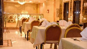 Ein Essbereich mit gedeckten Tischen, Stühlen mit Kopfstützen und einer Chandelier.