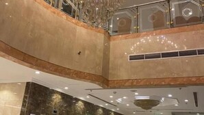 Ein mehrgeschossiges Interieur mit einem großen Chandelier, Marmorwänden und einer Glasreling.