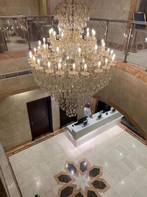 Un gran candelabro con múltiples velas, una mesa de recepción y un diseño geométrico en el suelo.