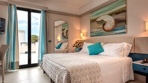 Hotelkamer met een groot bed, uitzicht door de glazen deur, een schilderij aan de muur en een nachtkastje met een lamp.