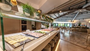 Een buffetgedeelte met diverse gerechten, een glazen vitrine en een zithoek met tafels en stoelen.