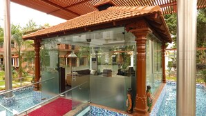 A glass-walled room with a red carpet, a pool, and traditional decor. - Jal Mahal Resort & Spa, Mysore (Mysore)