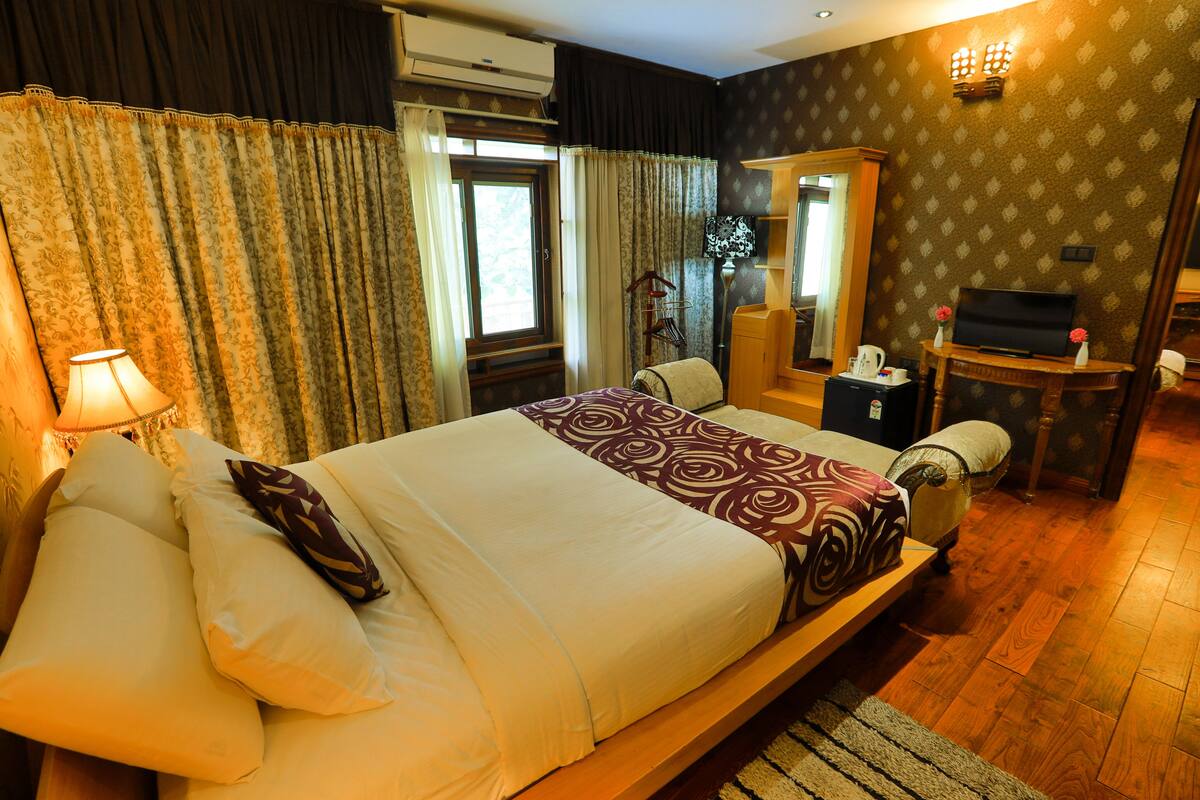 A well-appointed hotel room with a large bed, a desk, a chair, and a mirror.