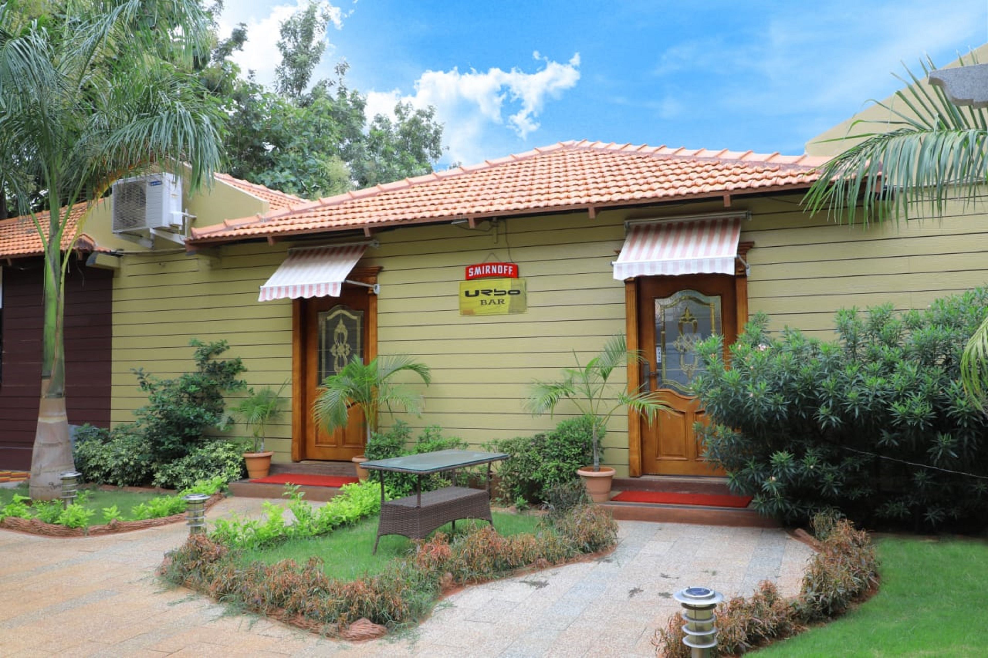A building with a tiled roof, a sign for 'SMIRNOFF URBO BAR', and a small outdoor seating area.