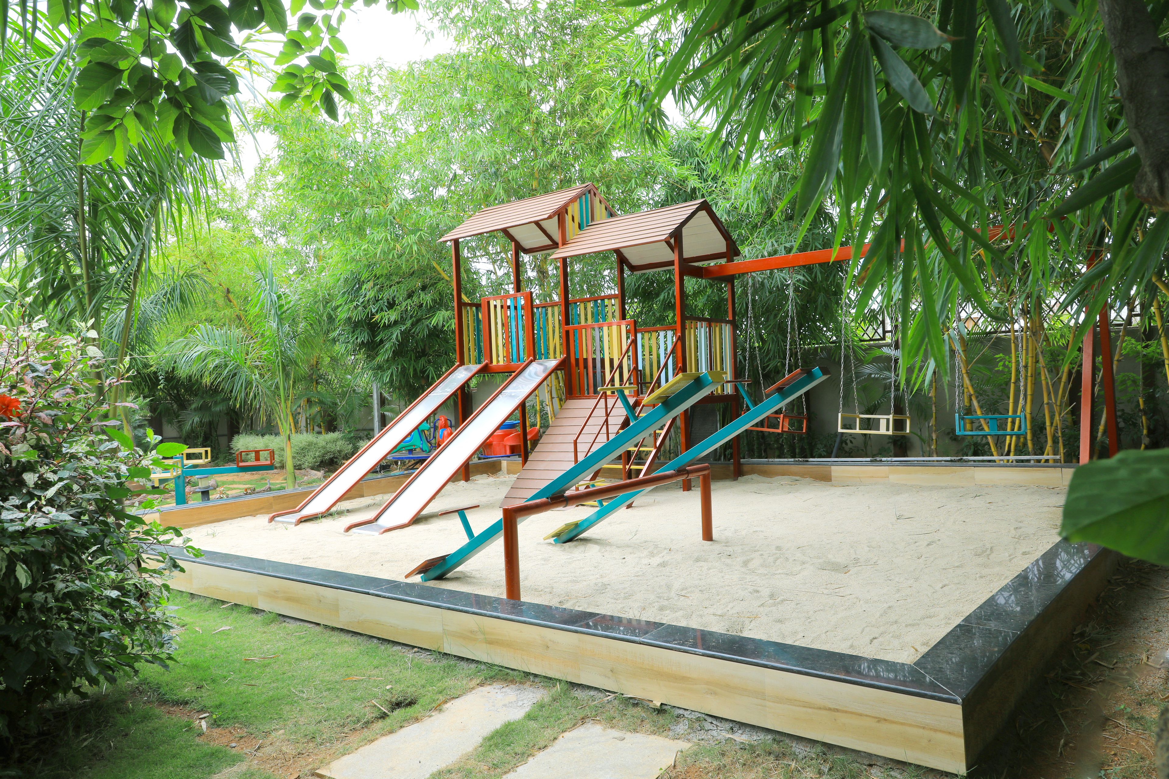 A playground with slides and swings surrounded by greenery.