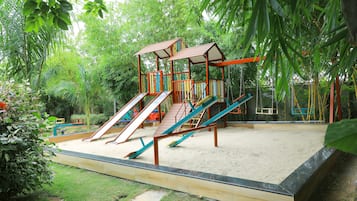 A playground with slides and swings surrounded by greenery.